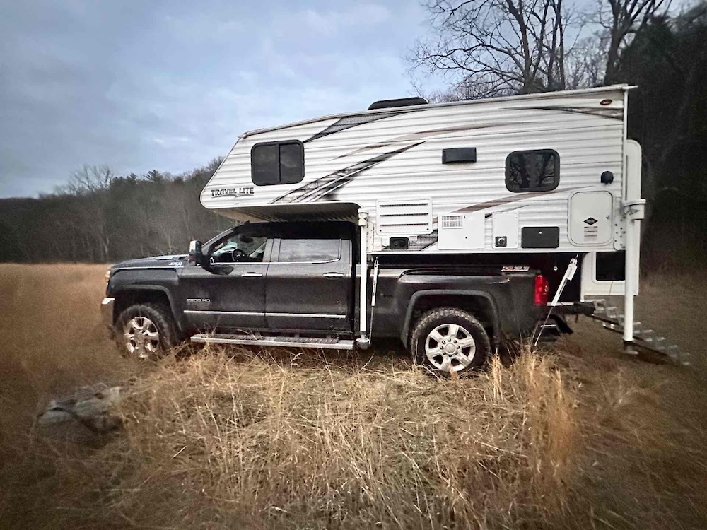 Truck camper setup off-grid in a field during weekend camping trip