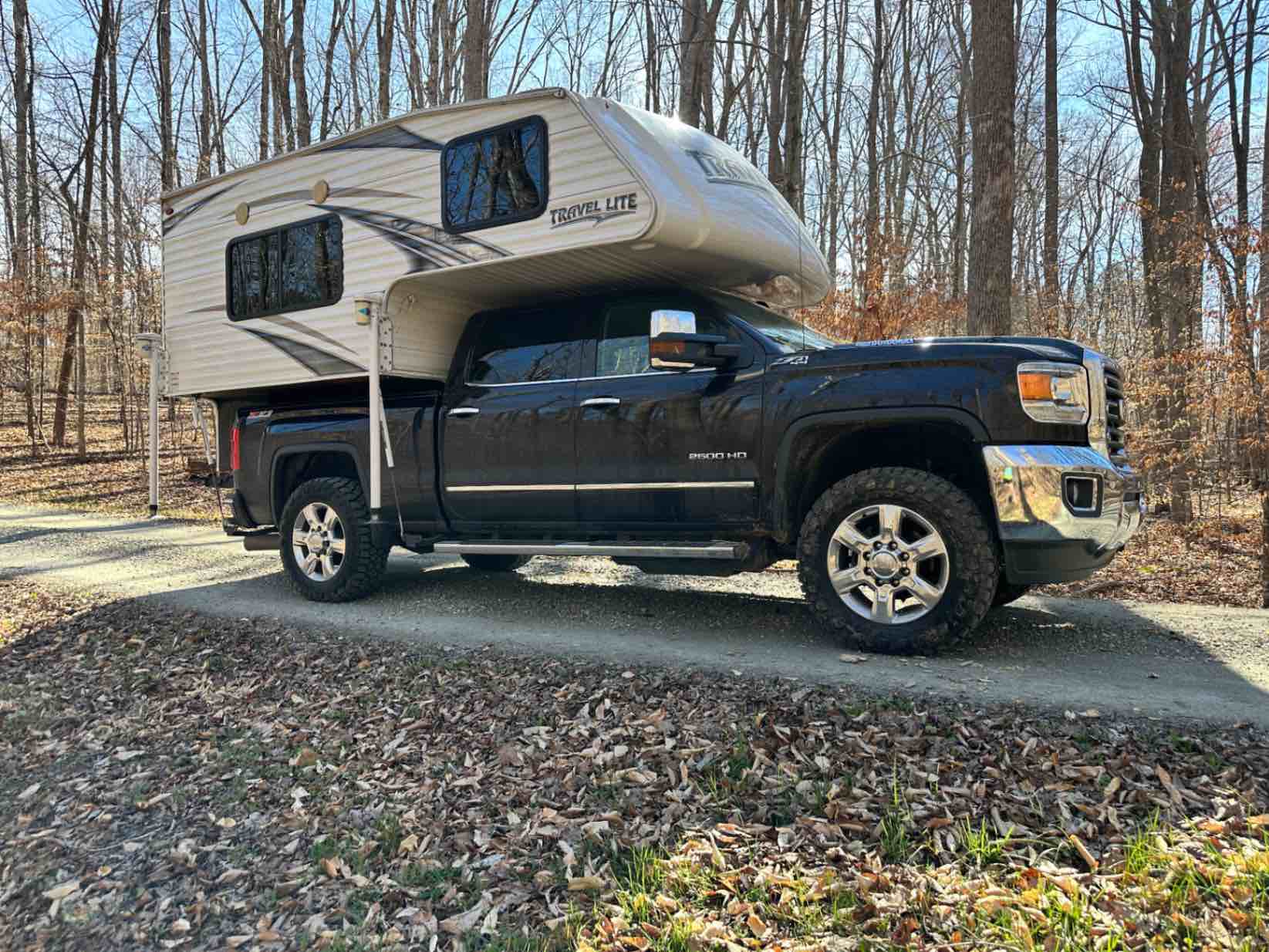 Truck camper parked at a campsite in the woods before setup