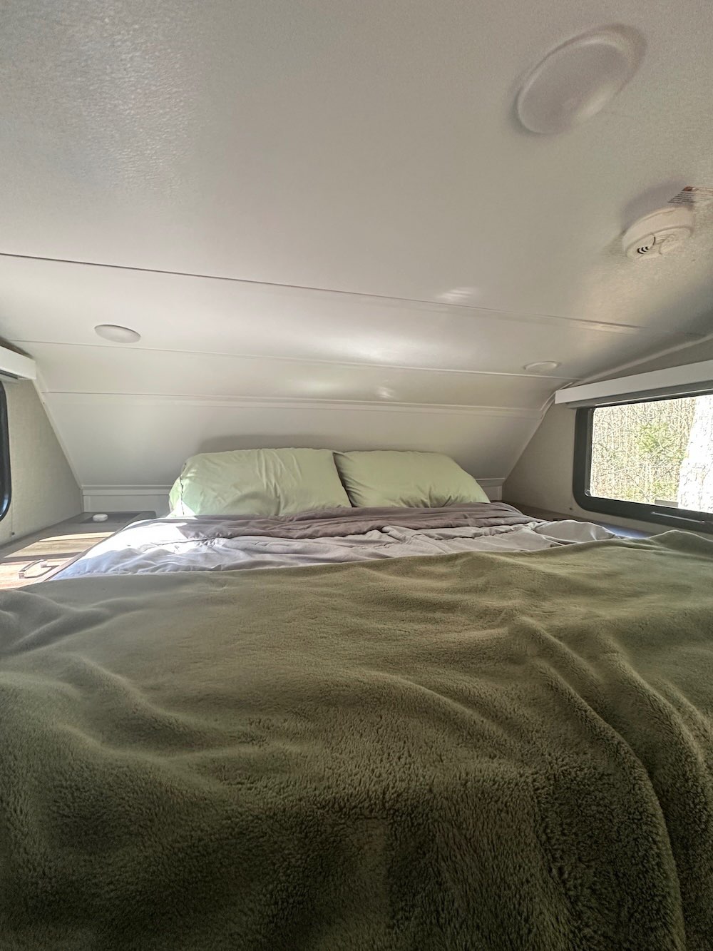 Cozy truck camper bed setup with pillows and blankets showing how we sleep comfortably in a truck camper
